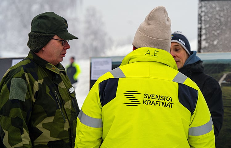 Man i militärkläder samtalar med en man i Svenska kraftnät-jacka