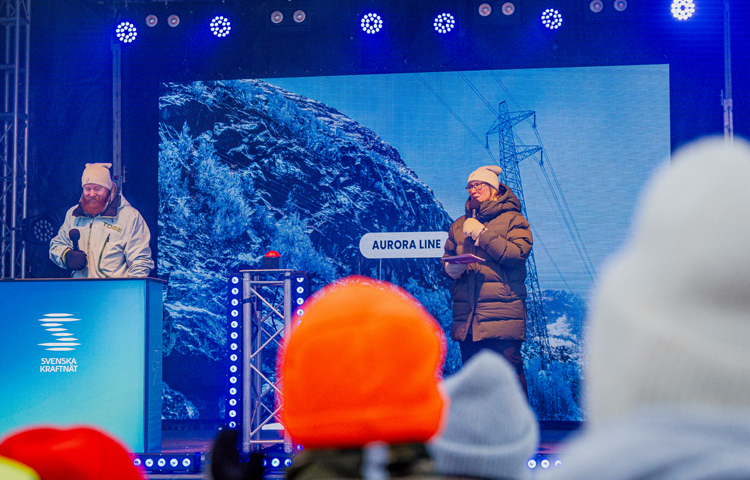 En man och en kvinna i mössor och varma kläder talar från en utomhusscen