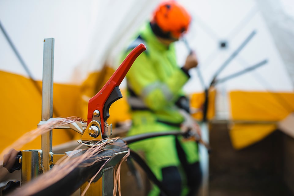 En person i varselkläder arbetar med kablar