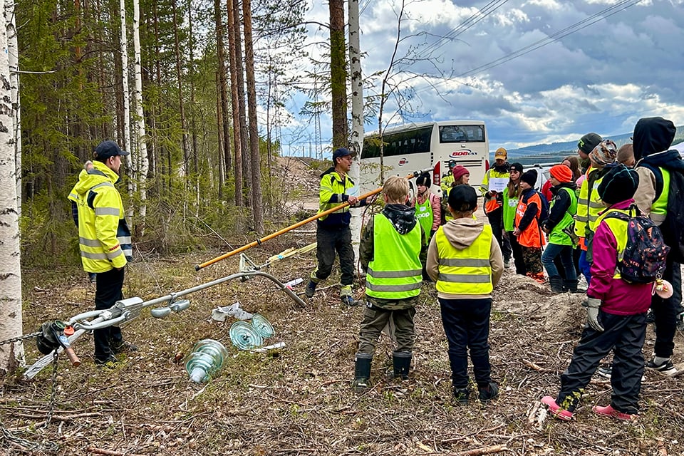 Pontus Kristiansen och Johnny Scherdin visar eleverna från Vuollerim hur det går till att dra en lina genom att ha spänt en mellan två träd.