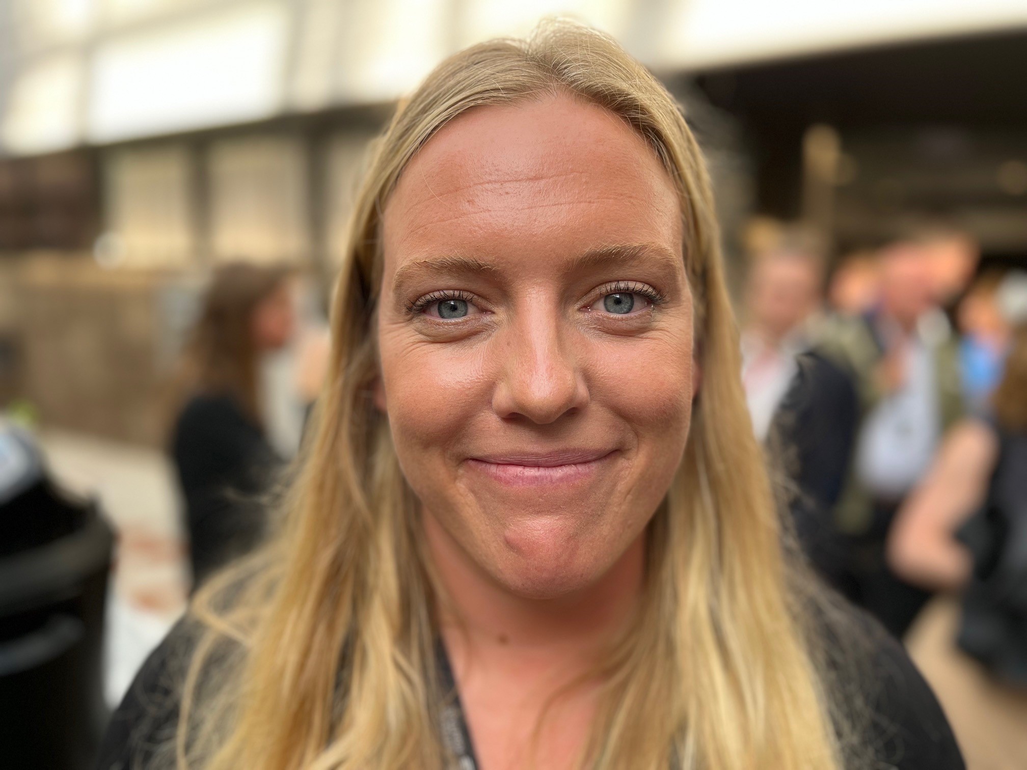 Porträttbild av kvinna, i bakgrunden syns ett myller av människor