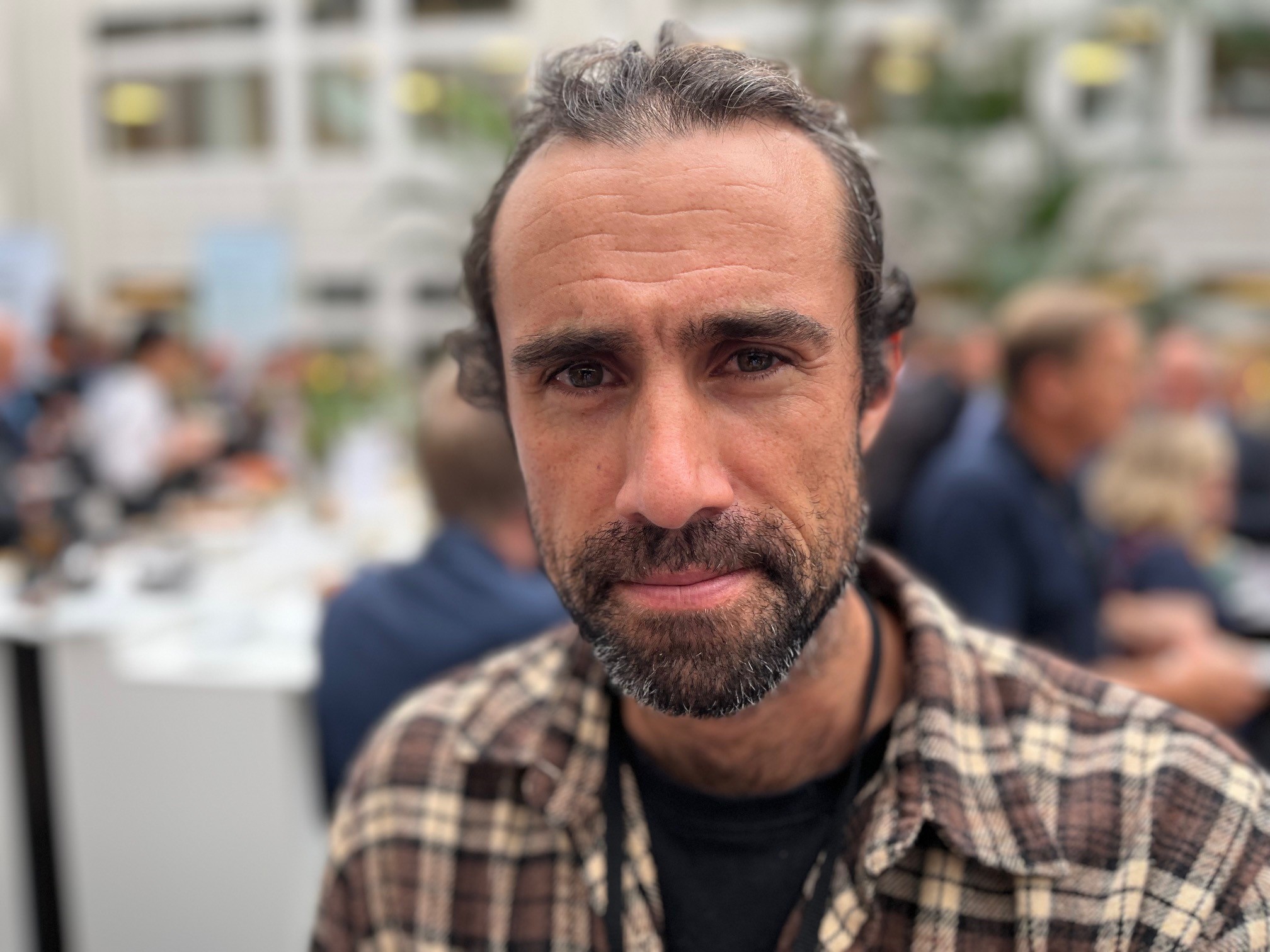 Porträttbild av en man, i bakgrunden syns ett myller av människor