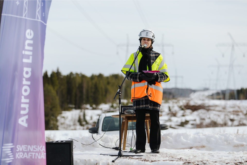 Lotta står på en scen av snö och talar