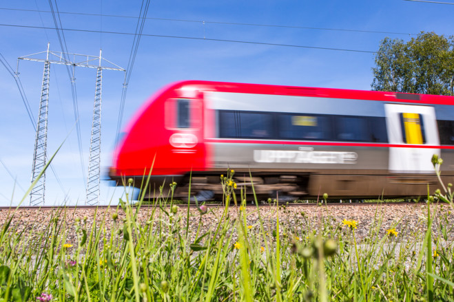 Bild på ett tåg som åker förbi framför en kraftledning