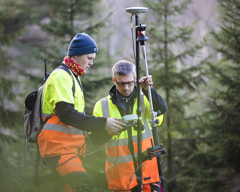 Två män i skogen med mätinstrument