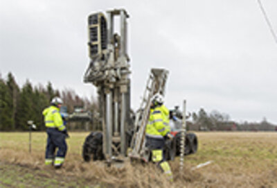 Två män i arbetskläder vid en  borrbandvagn