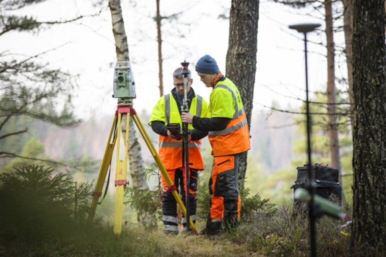 Bild på två arbetare som utför en fältundersökning