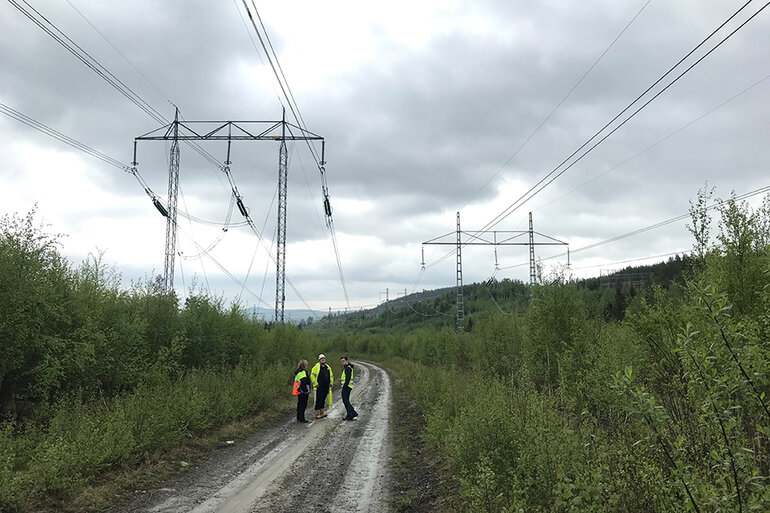 Grusväg under kraftledning i skogen. 