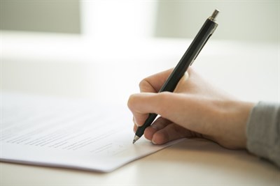 Närbild på hand som håller en penna för att signera ett papper.