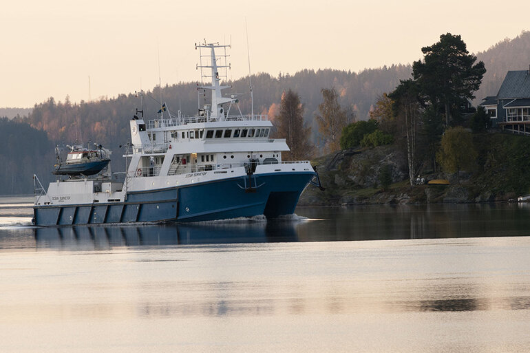 Vitt och blått fartyg glider fram mellan öar i skärgården