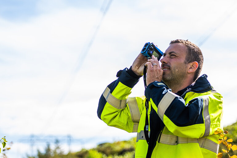 Man som tittar i ett mätinstrument för skogligt underhåll