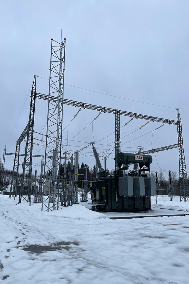 En gråkall vårvinterdag är stamnätstationen i Linnvasselv fotograferad. Stål. Lite snö ligger på marken framför stationsbyggnaden.