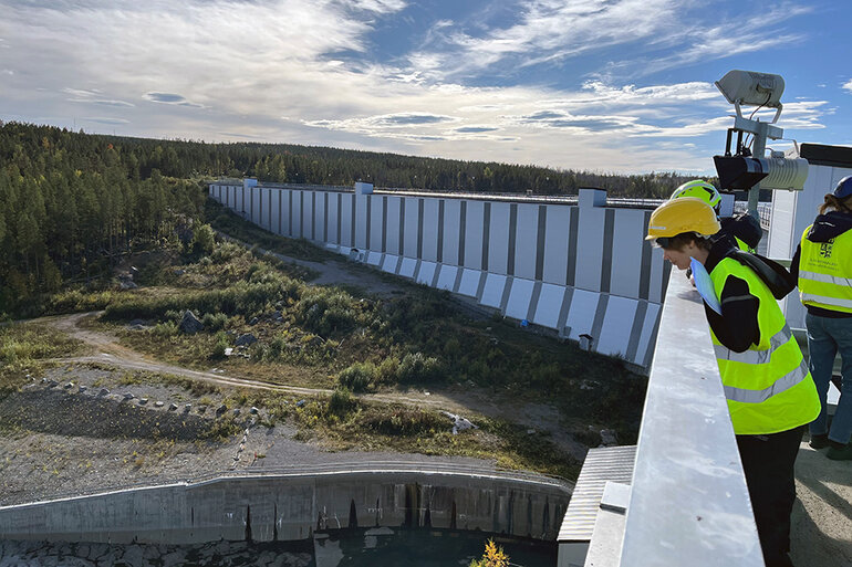 Kvinna med arbetshjälp tittar ner i en dammanläggning