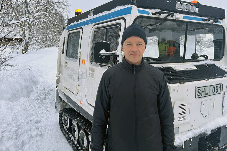 Man står framför en vit bandvagn i en snöig miljö