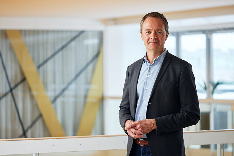 Man i kavaj står i ett kontorslandskap