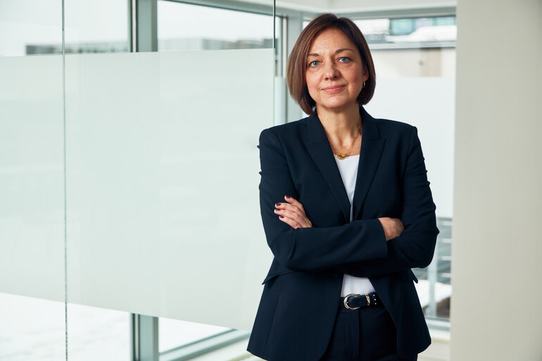 Viktoria Neimane står med armarna i kors och tittar in i kameran, bakgrunden är kontorsmiljö