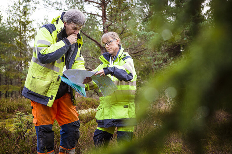 Man och kvinnas i skog som tittar på en karta